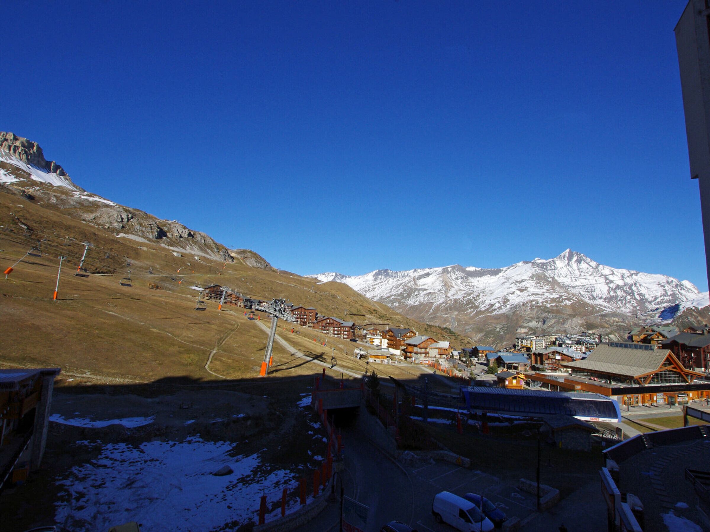 A mountain resort with snow-covered peaks, a ski lift, and traditional wooden buildings.