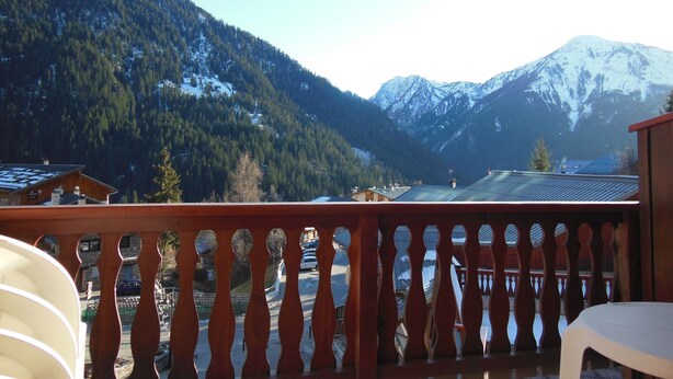 Ein Balkon mit Blick auf schneebedeckte Berge und ein bewaldetes Tal.