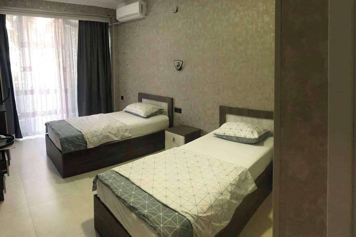 A hotel room with two beds, a shower, and a toilet.