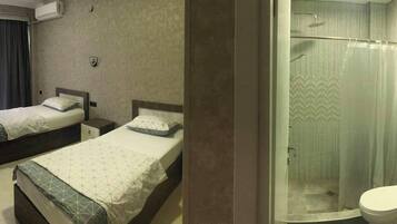 A hotel room with two beds, a shower, and a toilet.