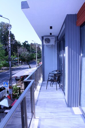 A balcony with a table and chairs, an air conditioning unit, and a view of the street. - Golden Lion (Kobuleti)