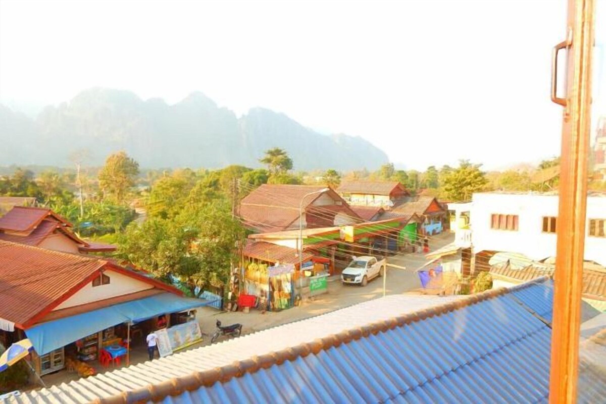 A rural village with traditional houses, a small market, and a mountain in the background.