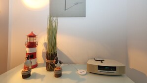 Ett rum med en modell av ett fyrtorn, en växt, en liten fågelstatyett och en radio på ett bord.