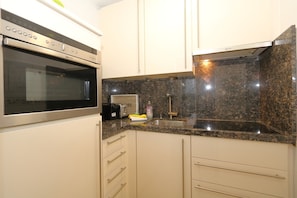 A kitchen with a built-in oven, a granite countertop, a sink, and a toaster.