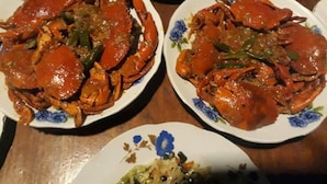 Deux assiettes de crabe cuit, accompagné de légumes, sur une table en bois.