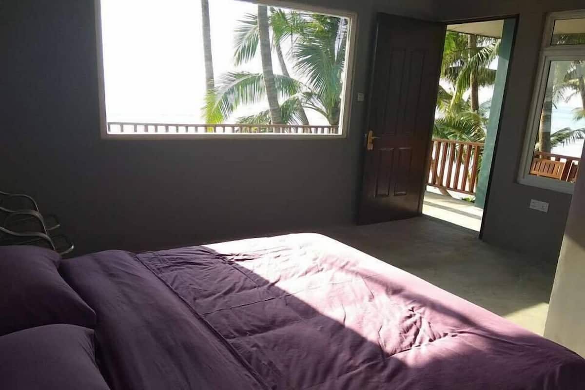 Une chambre à coucher avec un lit, une fenêtre et une porte donnant sur un balcon.