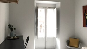 Una habitación con una mesa de madera oscura, una silla, una planta pequeña y una puerta que da a un espacio exterior.