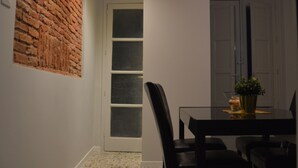 Un comedor con una pared de ladrillo decorativa, piso de baldosas y una mesa con sillas.