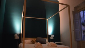 Un dormitorio con cama con dosel, dos lámparas de noche y una mesita de noche.