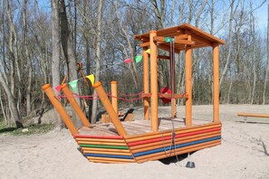A wooden swing set with a platform, chains, and colorful flags.