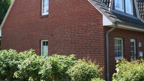 A red brick building with a sloped roof and a dormer window. - Vacation apartment Reinhardt (Sylt-Ost)