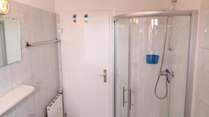 A modern bathroom with a glass shower enclosure, a white sink, and a towel rack. - Vacation apartment Reinhardt (Sylt-Ost)