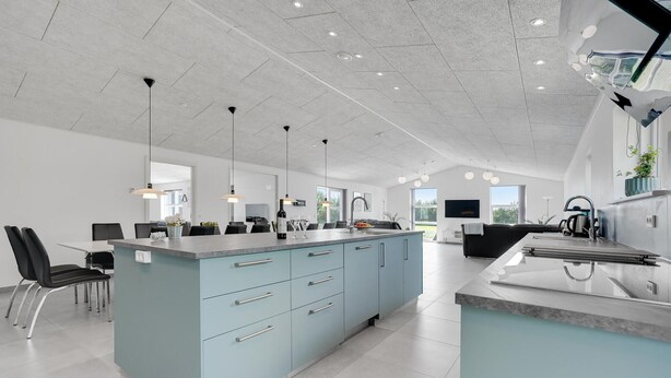 A modern kitchen with a central island, black chairs, and a dining area with a table and chairs. - Lovely home in Jerup with sauna (Jerup)