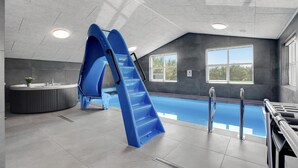 An indoor swimming pool with a blue slide, a hot tub, and large windows. - Lovely home in Jerup with sauna (Jerup)