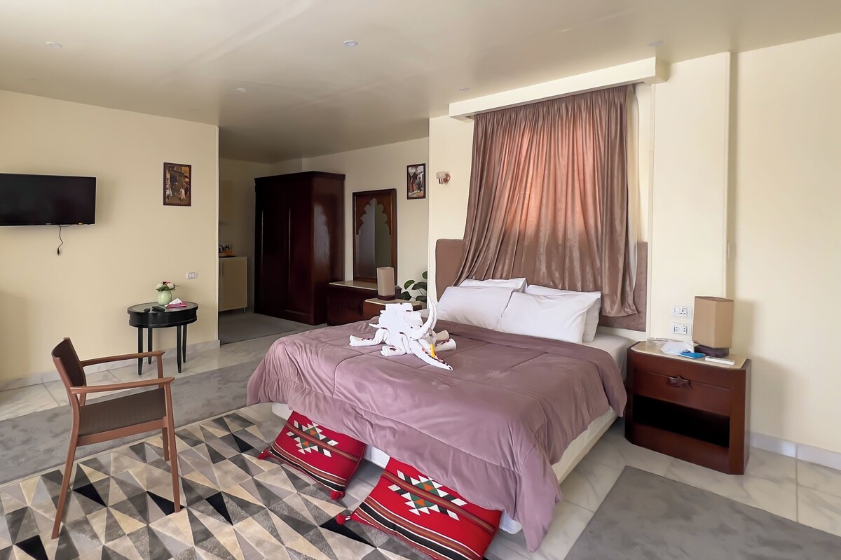 Una habitación de hotel con cama, escritorio, silla, televisión y armario.