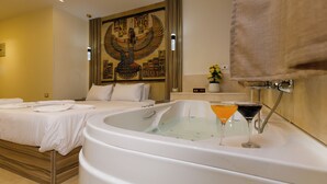 A hotel room with a large bathtub, a bed with white linens, and a wall mural of an Egyptian figure. - Sun Pyramids View Inn (Giza)