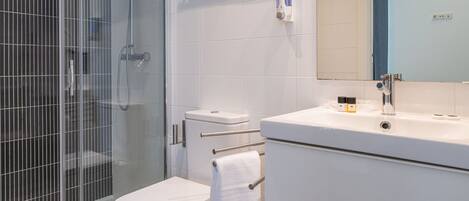 A modern bathroom with a glass-enclosed shower, a toilet, and a vanity with a mirror.
