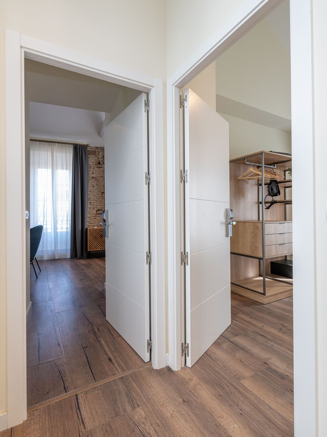 Una habitación moderna con suelo de madera, pared de ladrillo y armario empotrado con espejo y espacio para colgar ropa.