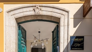 A building entrance with a stone archway, green doors, a staircase leading inside, and a sign for HomeArt Apartments. - Homeart Apartments Malaga (Málaga)