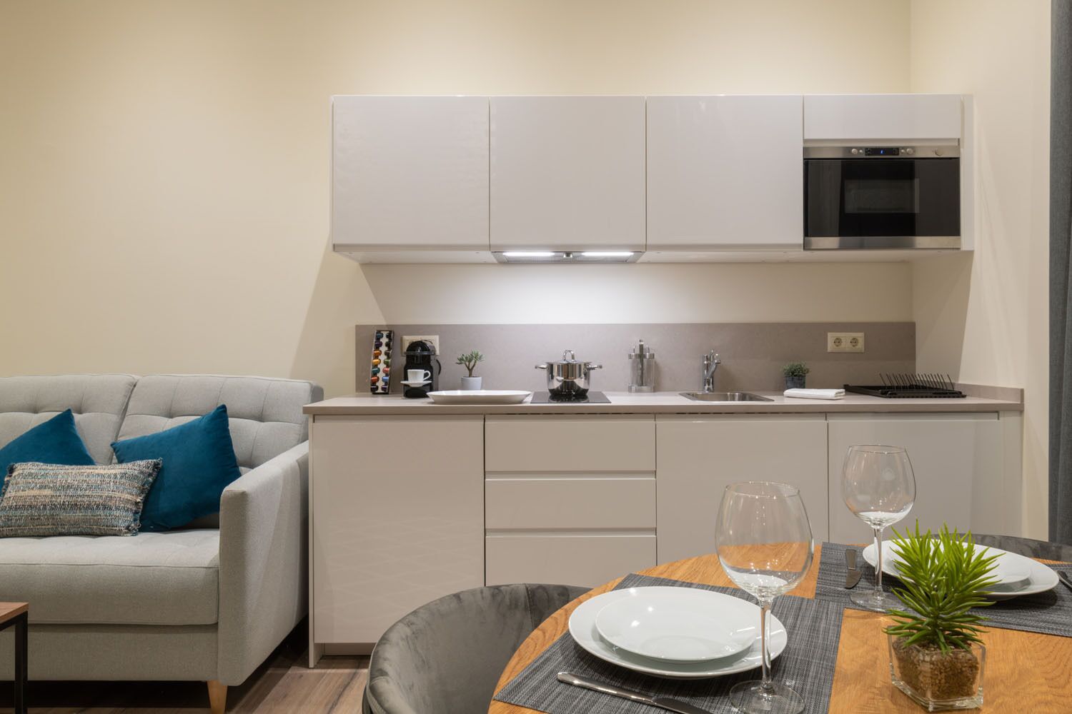 A modern kitchen with white cabinets, a built-in oven, and a dining area with a table set for two.