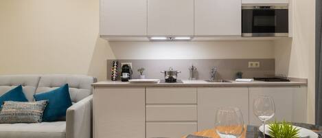 A modern kitchen with white cabinets, a built-in oven, and a dining area with a table set for two.