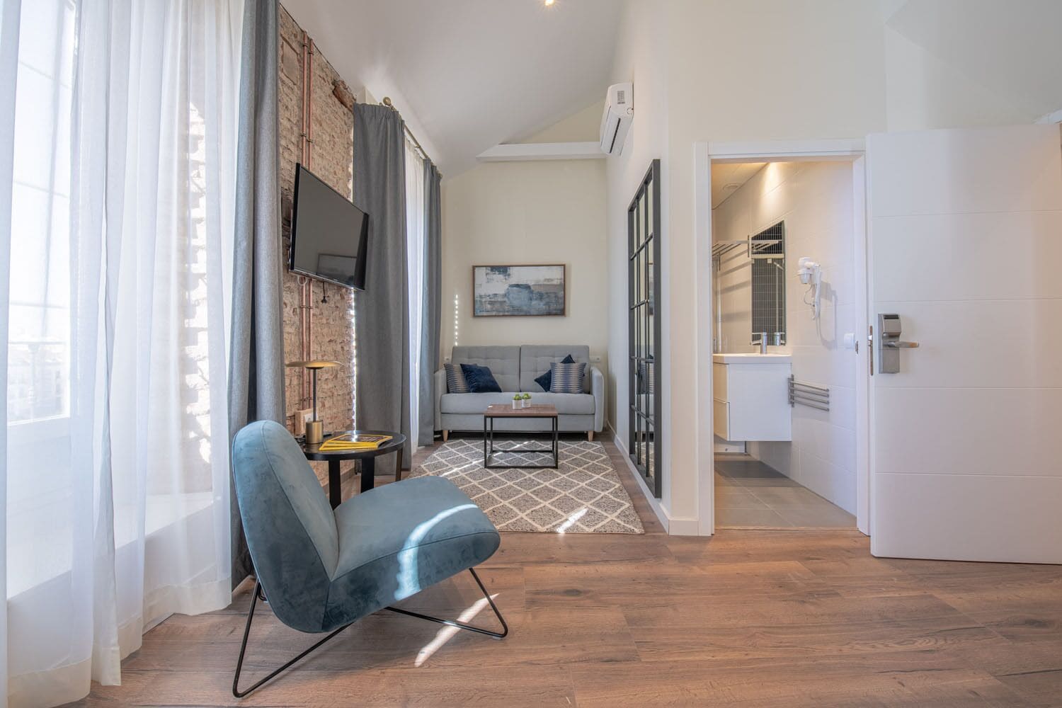 Una sala de estar moderna con un sofá, una mesa de centro y un televisor montado en la pared.