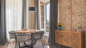 A dining area with a round table, chairs, a cabinet, and a brick wall. - Homeart Apartments Malaga (Málaga)