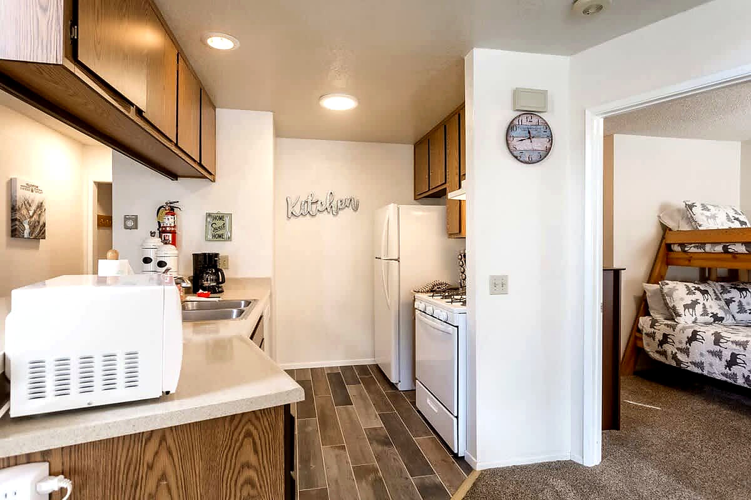 A compact kitchen with wooden cabinets, a refrigerator, a stove, and a microwave.