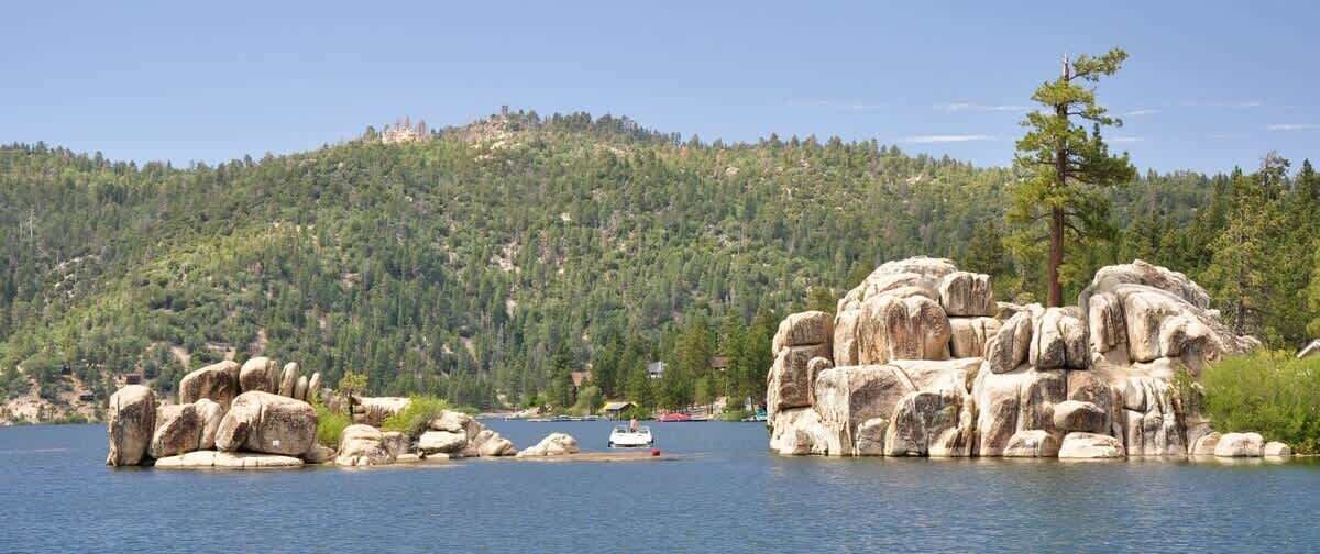 A lake with large boulders and a boat in the distance.