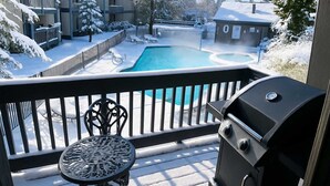 A balcony with a barbecue grill, a pool, and snow-covered surroundings.