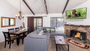 A living room with a fireplace, a dining area, and a TV mounted on the wall.