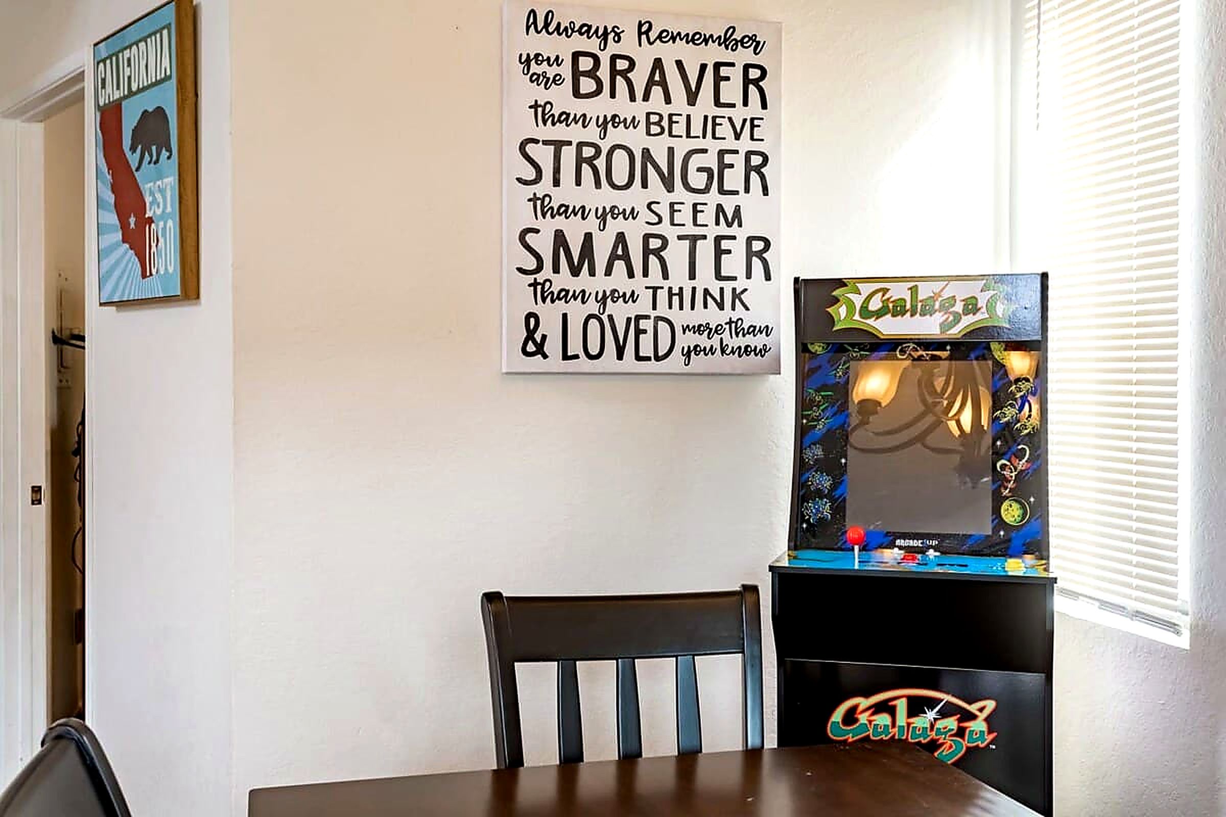 Een kamer met een inspirerende poster, een tafel met een stoel en een videospelconsole.