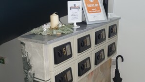 A reception desk with numbered drawers, a framed award certificate, a candle, and a decorative vase. - Hotel Gartenstadt (Dortmund)