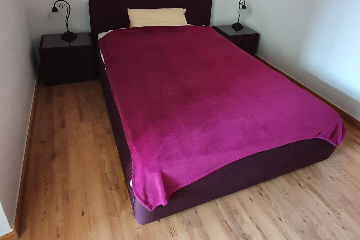 A bedroom with a bed, two bedside tables, and a wooden floor.