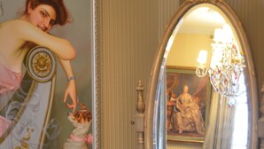 Une pièce comprenant un grand miroir décoratif, une chaise en bois et un tableau accroché au mur.
