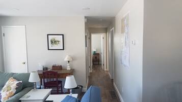 Un salon avec un canapé vert, un canapé bleu, une petite table avec une lampe et un tableau encadré au mur.