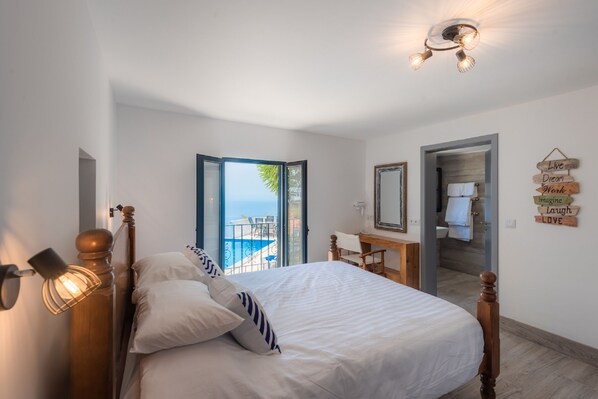 A bedroom with a bed, a desk, and a view of the sea. - Blue Ocean Villa. Magnificent Ocean view. Private Heated Pool. Quiet. AC. Garden (Faja da Ovelha, Calheta, Madeira)