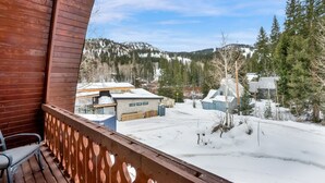 Un balcon en bois offrant une vue sur un paysage enneigé, avec des bâtiments et des arbres.