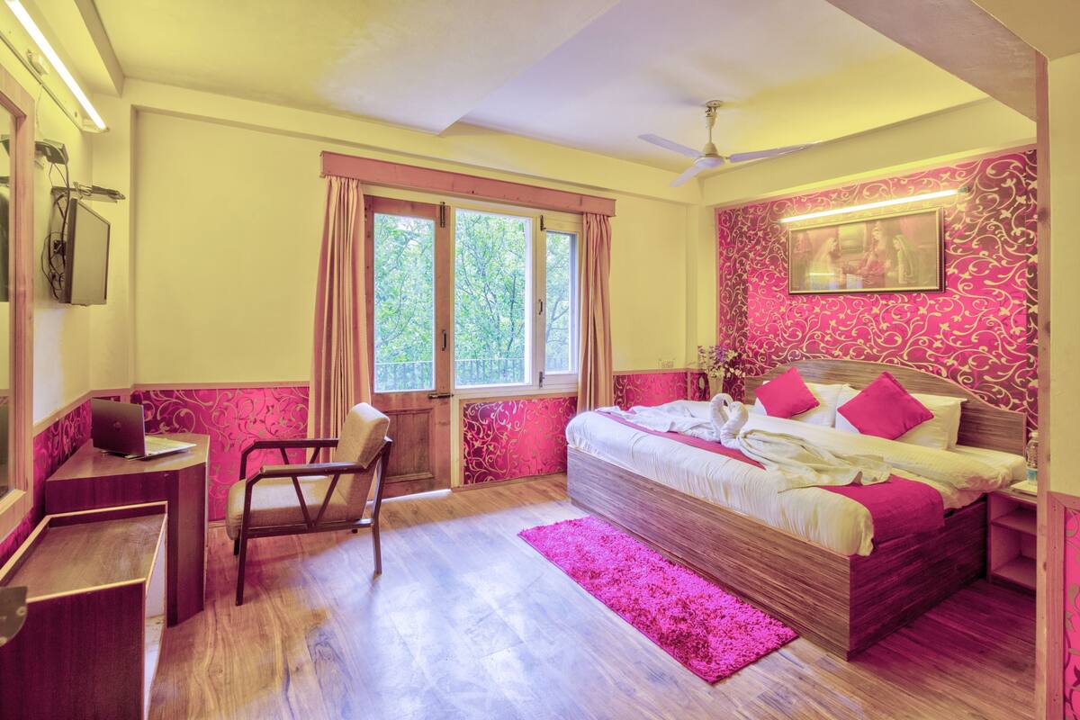 Ein Schlafzimmer mit einem hölzernen Bett, einem Schreibtisch, einem Stuhl und einem Fenster mit Vorhängen.