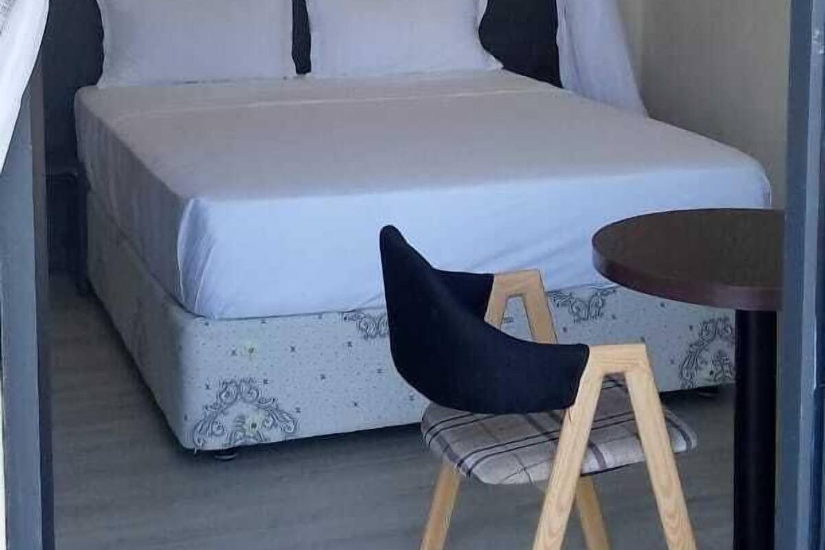 A bedroom with a bed, a small table, and a chair.