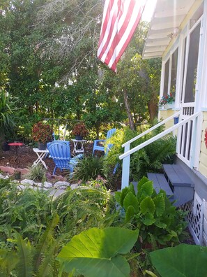 A covered outdoor seating area with blue chairs, a table, and a potted plant.