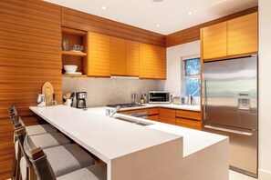 A modern kitchen with wooden cabinetry, a stainless steel refrigerator, and a large island with a sink.
