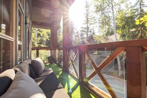Una habitación soleada con vista a una calle, una terraza de madera y un sofá.