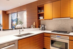 Eine moderne Küche mit Holzausstattung, einem Edelstahlherd und einem eingebauten Backofen.