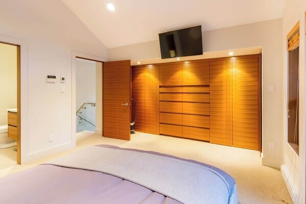 Un dormitorio con cama, armario de madera, televisor y baño.