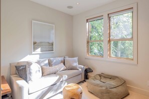 A modern living room with a sofa, a dog bed, and a framed picture on the wall.