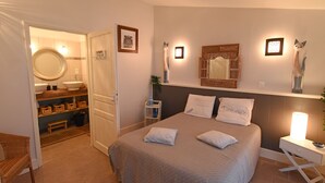 Une chambre à coucher avec un lit, une table de chevet, une commode et un miroir au-dessus du lit.