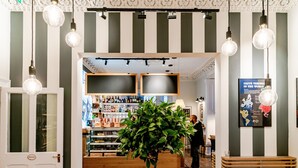 A modern interior with striped walls, hanging light fixtures, a wooden reception desk, and a large potted plant. - The Strand Hotel, the former residence of Oscar Wilde (Bray)