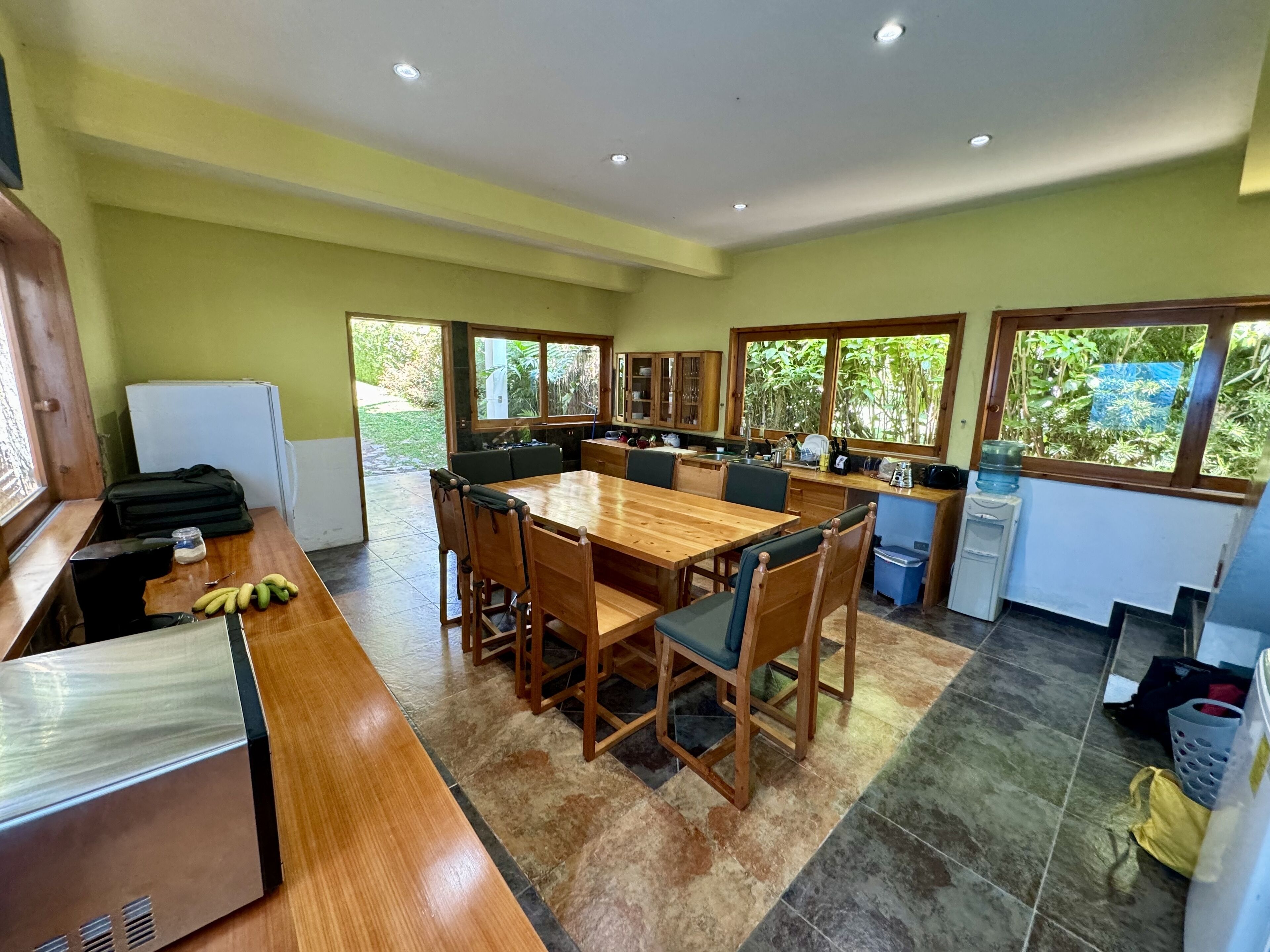 Una cocina amplia con una mesa de comedor de madera, sillas y un refrigerador.