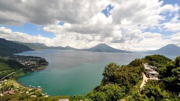 A panoramic view of a coastal town with a large body of water, mountains in the background, and a clear sky.